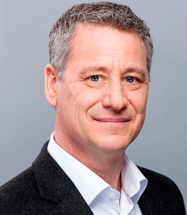 Bertrand Labelle is smiling and wearing a black coat with a white shirt
