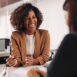Black woman with business clothes smiling to another woman